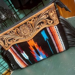 Description
Genuine leather hand tooled crossbody with side fringe accents.